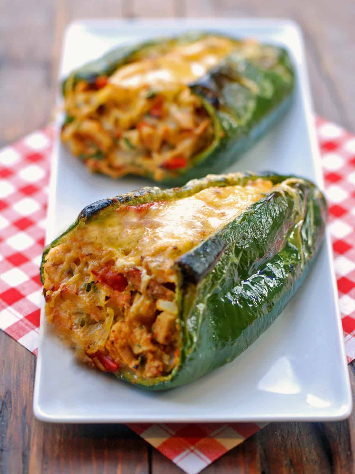 Two stuffed poblano peppers are served on a white tray.