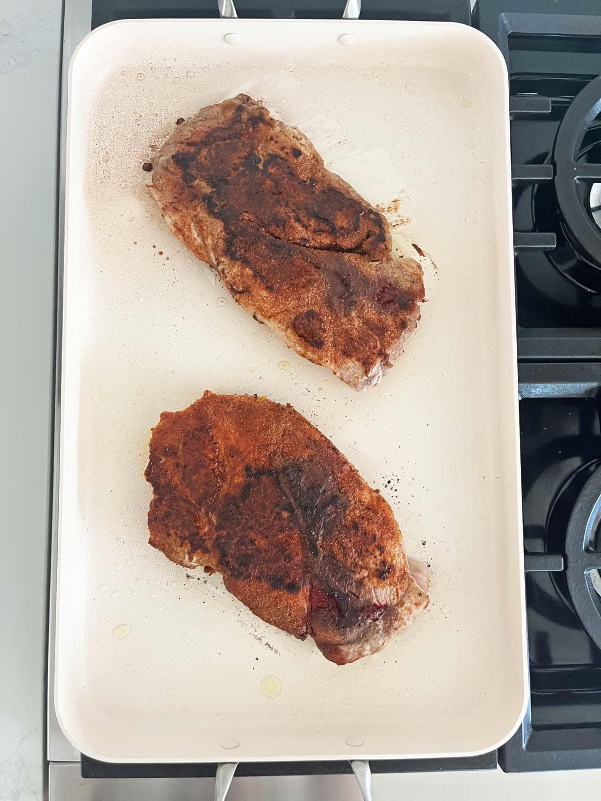 Cooking two pork steaks on a double-burner griddle.