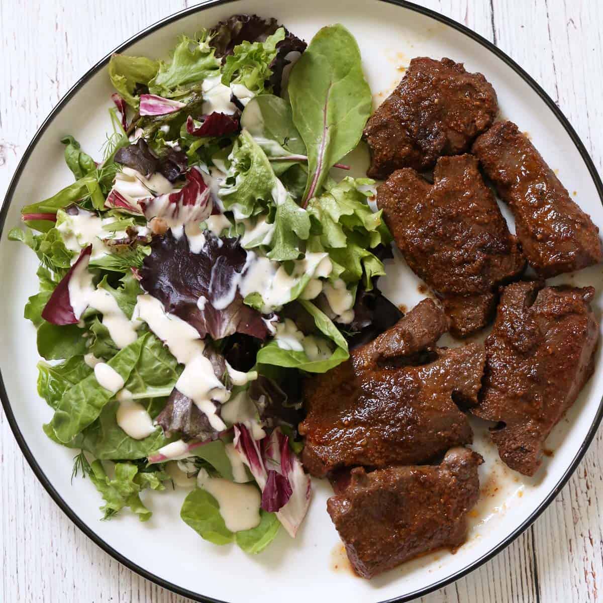 Pan-fried beef heart is served with a salad.