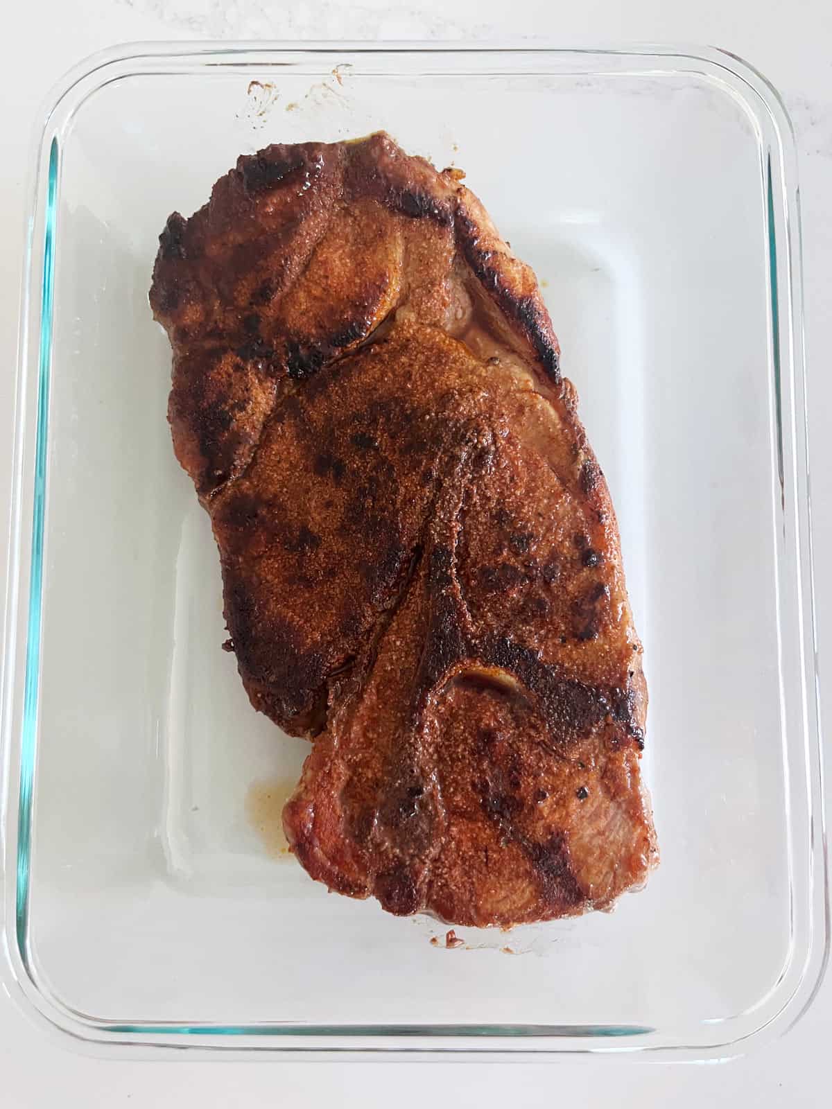 A leftover pork steak in a food storage container.