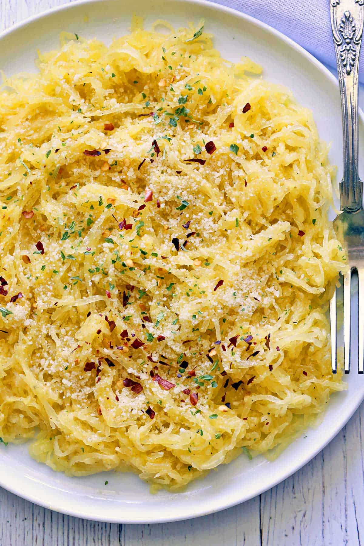 Spaghetti squash pasta is served on a white plate with a fork.