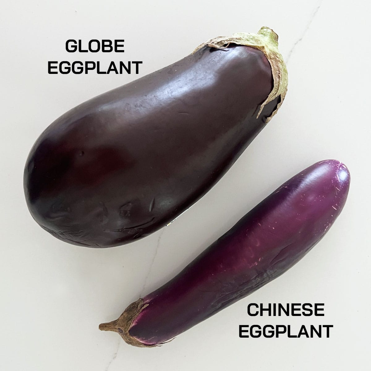 A globe eggplant and a Chinese eggplant next to each other.
