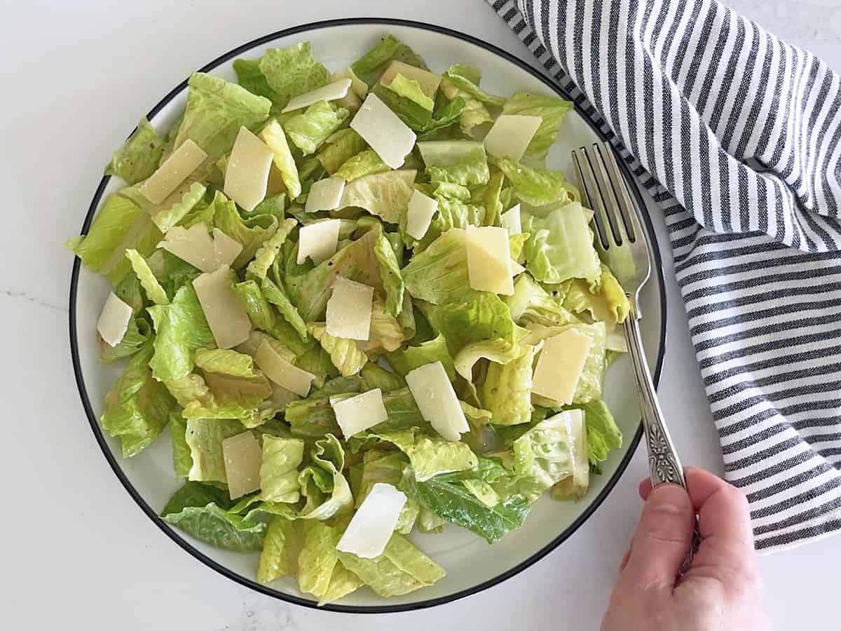 The salad is served with a napkin and a fork.