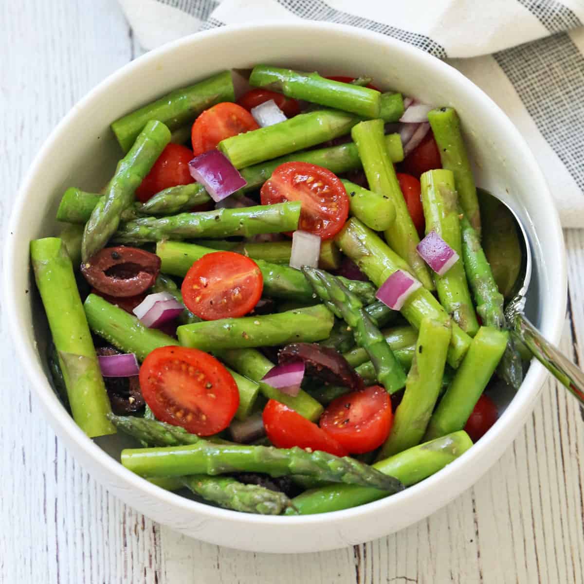 Asparagus salad is served in a white bowl.