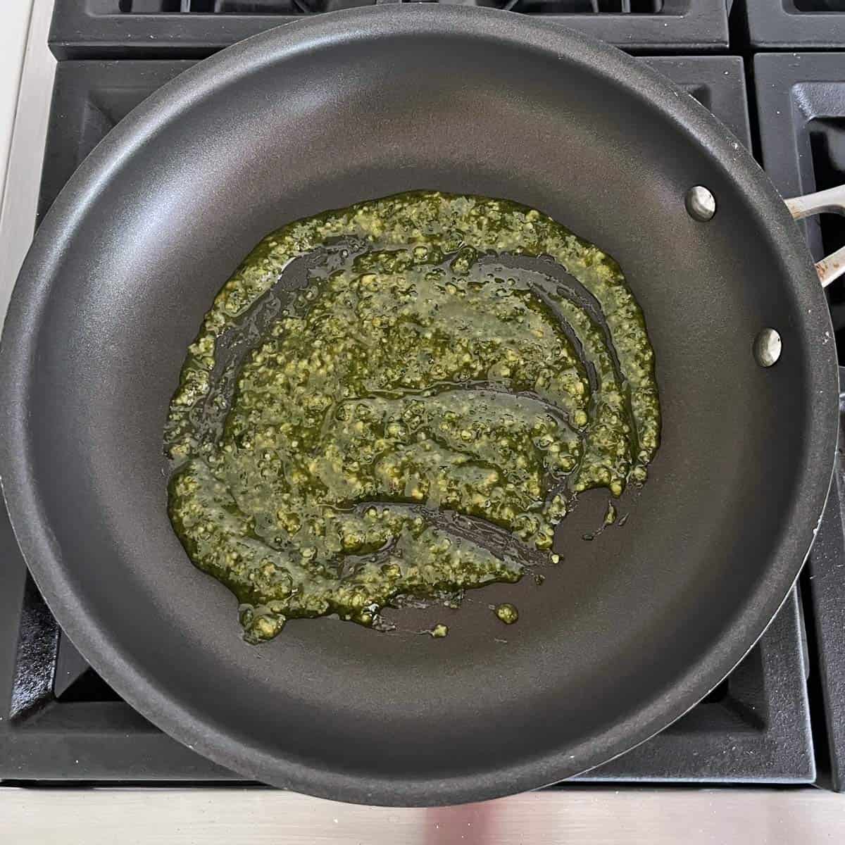 Heating pesto sauce in a nonstick skillet.
