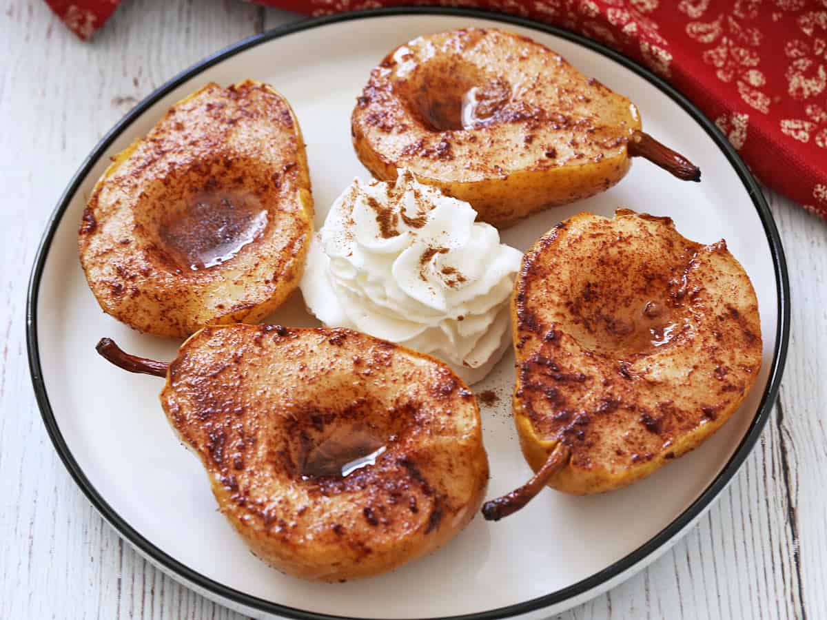 Baked pears are served with whipped cream.