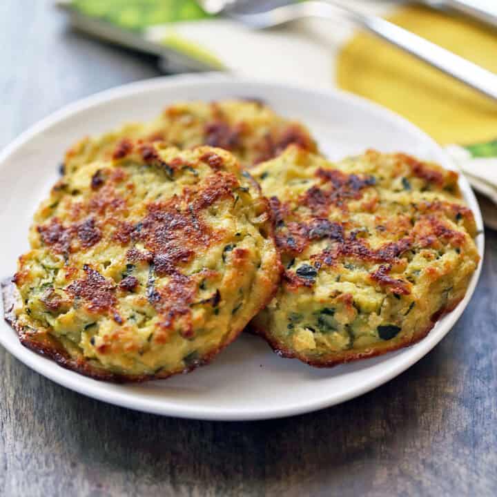 Three baked zucchini fritters on a plate.