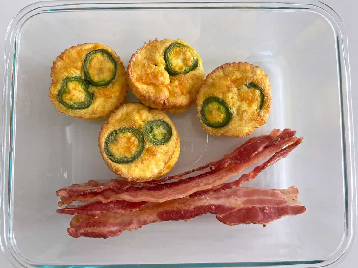 Egg muffins and bacon leftovers are kept in a glass food storage container.