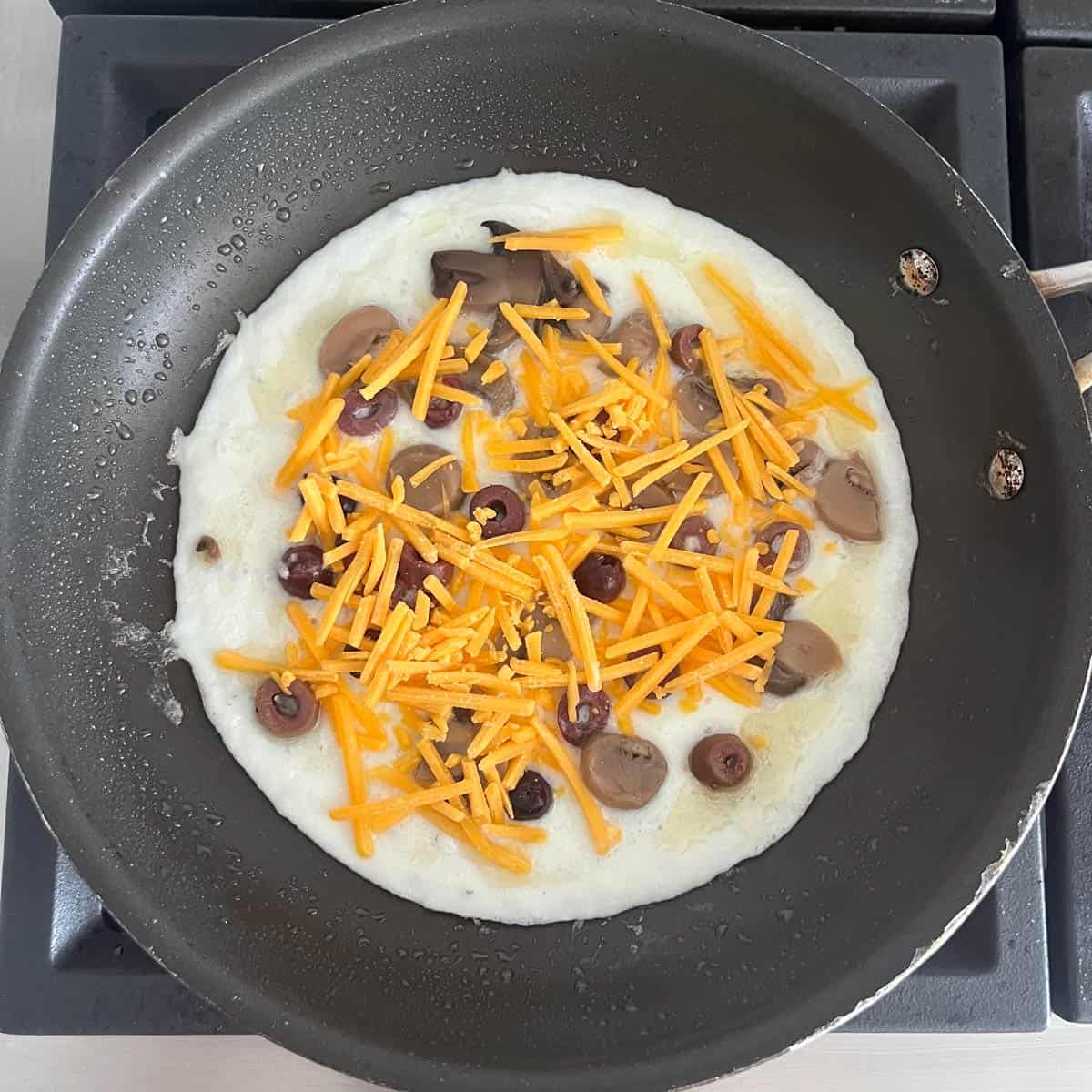 The omeletter is filled with mushrooms, olives, and cheddar.