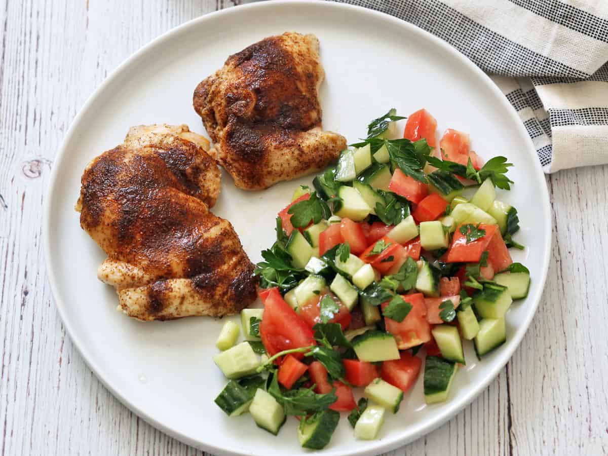 Israeli salad is served as a side to boneless chicken thighs.