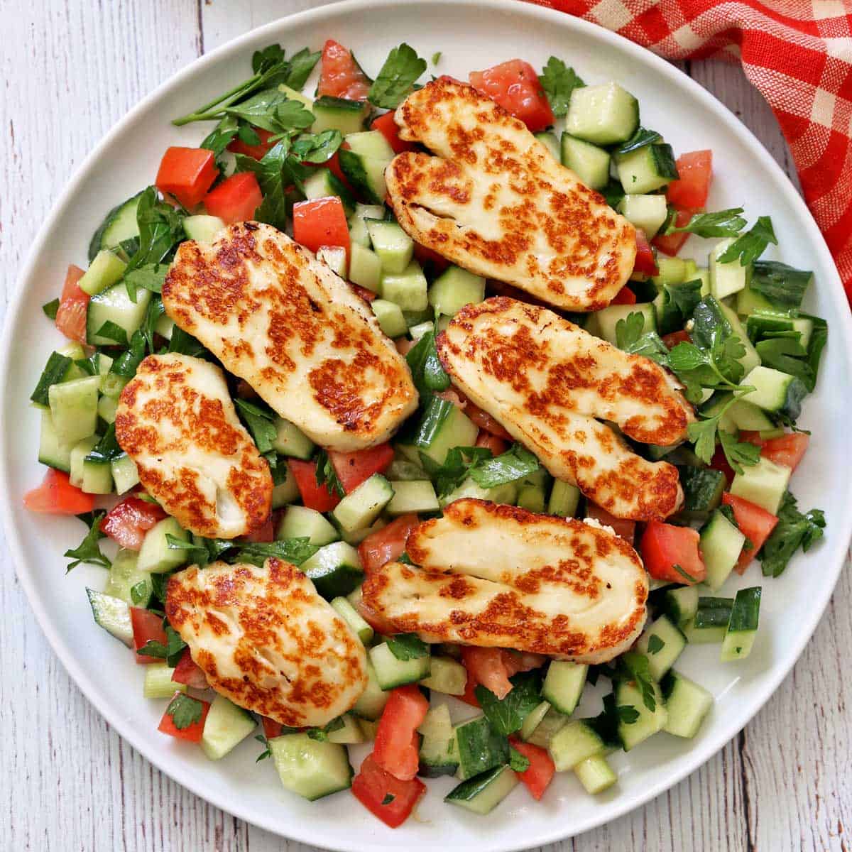 Israeli salad is topped with halloumi cheese.