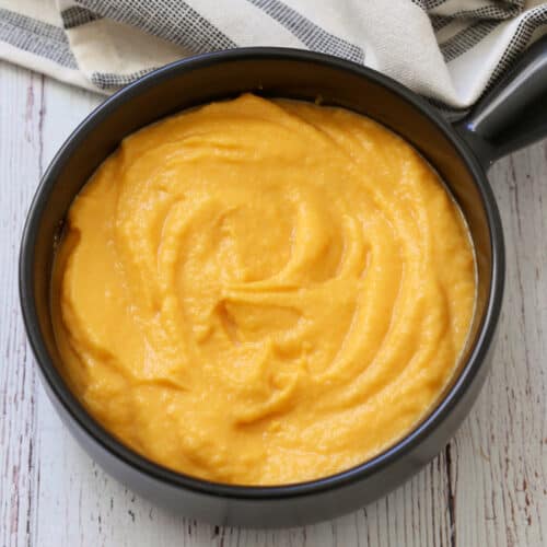 Mashed butternut squash is served in a bowl with a striped napkin.