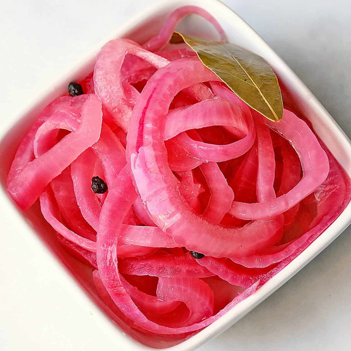 Pickled red onions are served in a bowl.