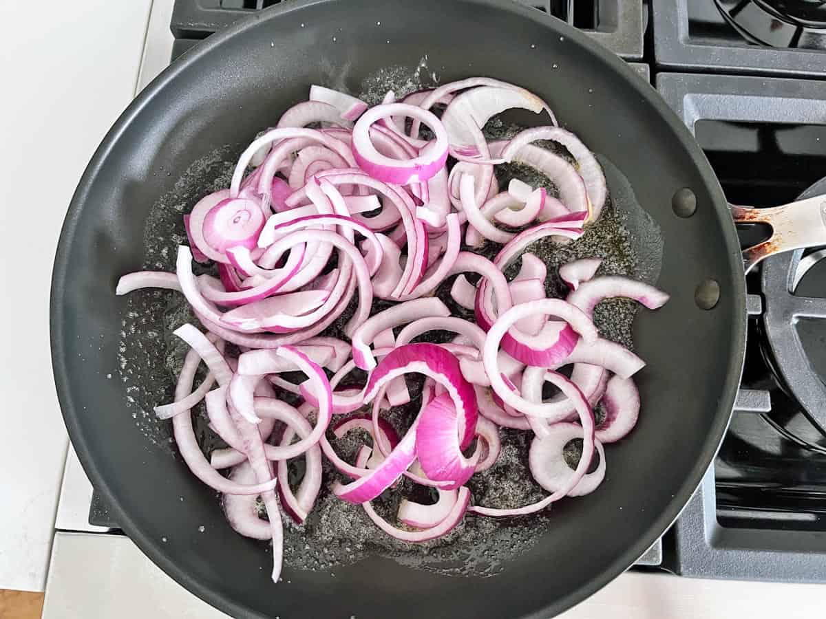 Raw red onions in a skillet.