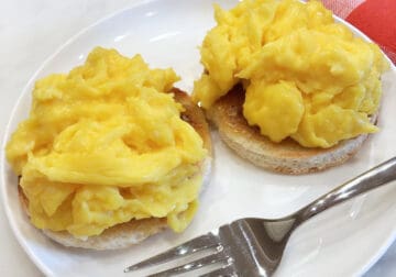 Scrambled eggs are served on an English muffin.