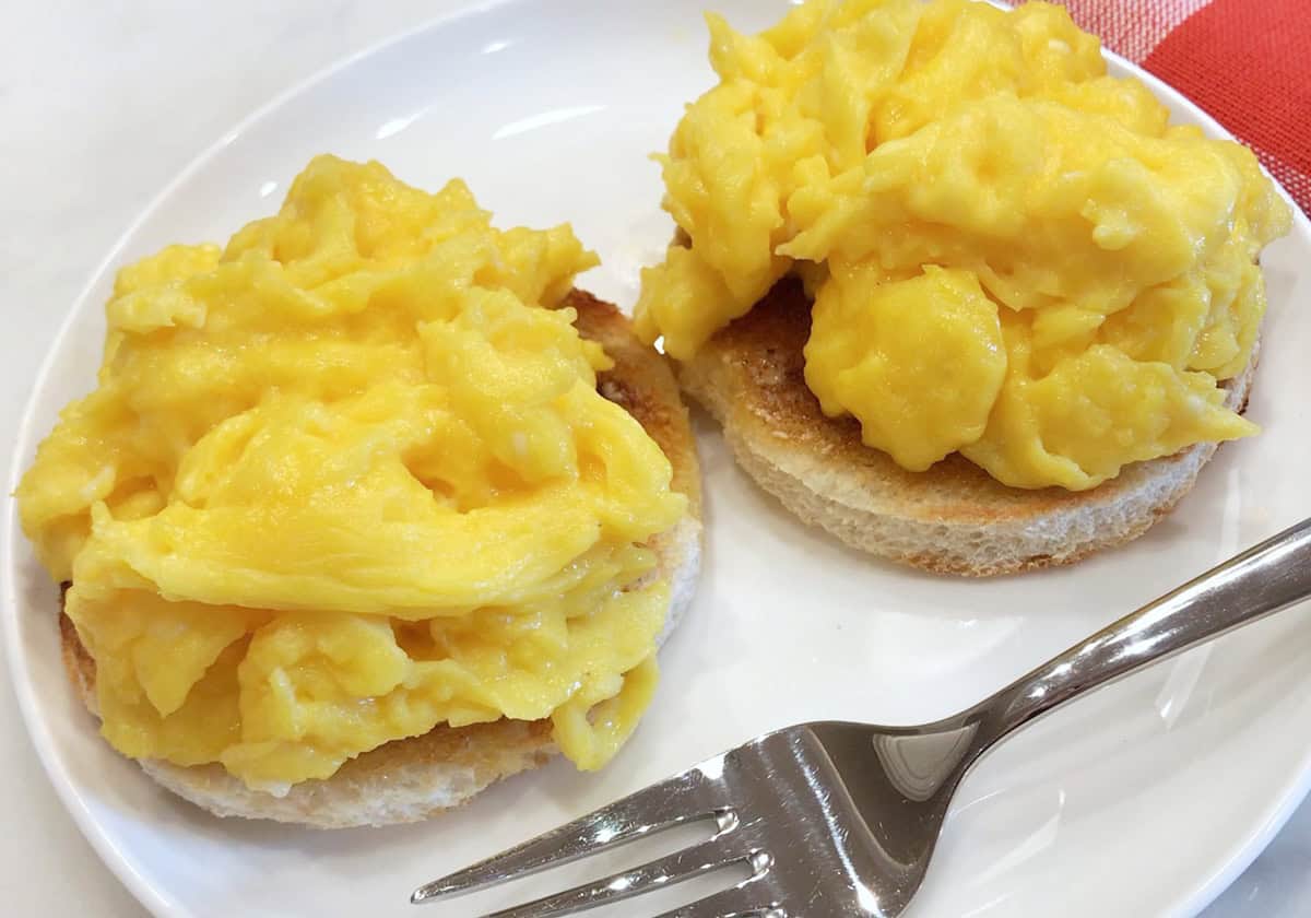 Scrambled eggs are served on an English muffin.