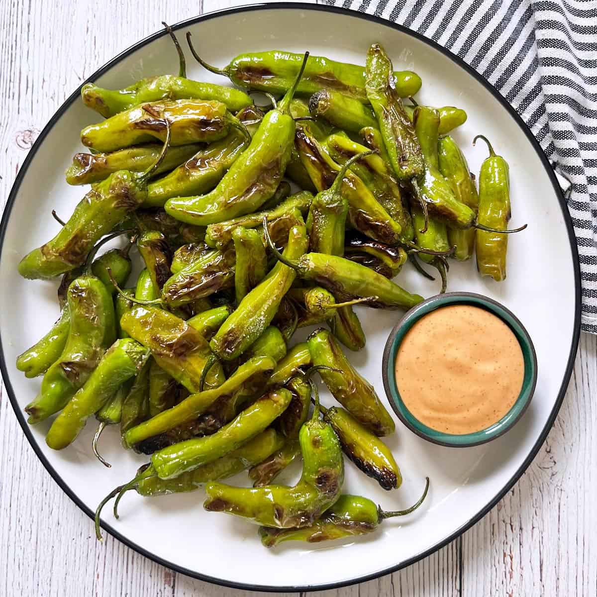 Shishito peppers are served with a dipping sauce.