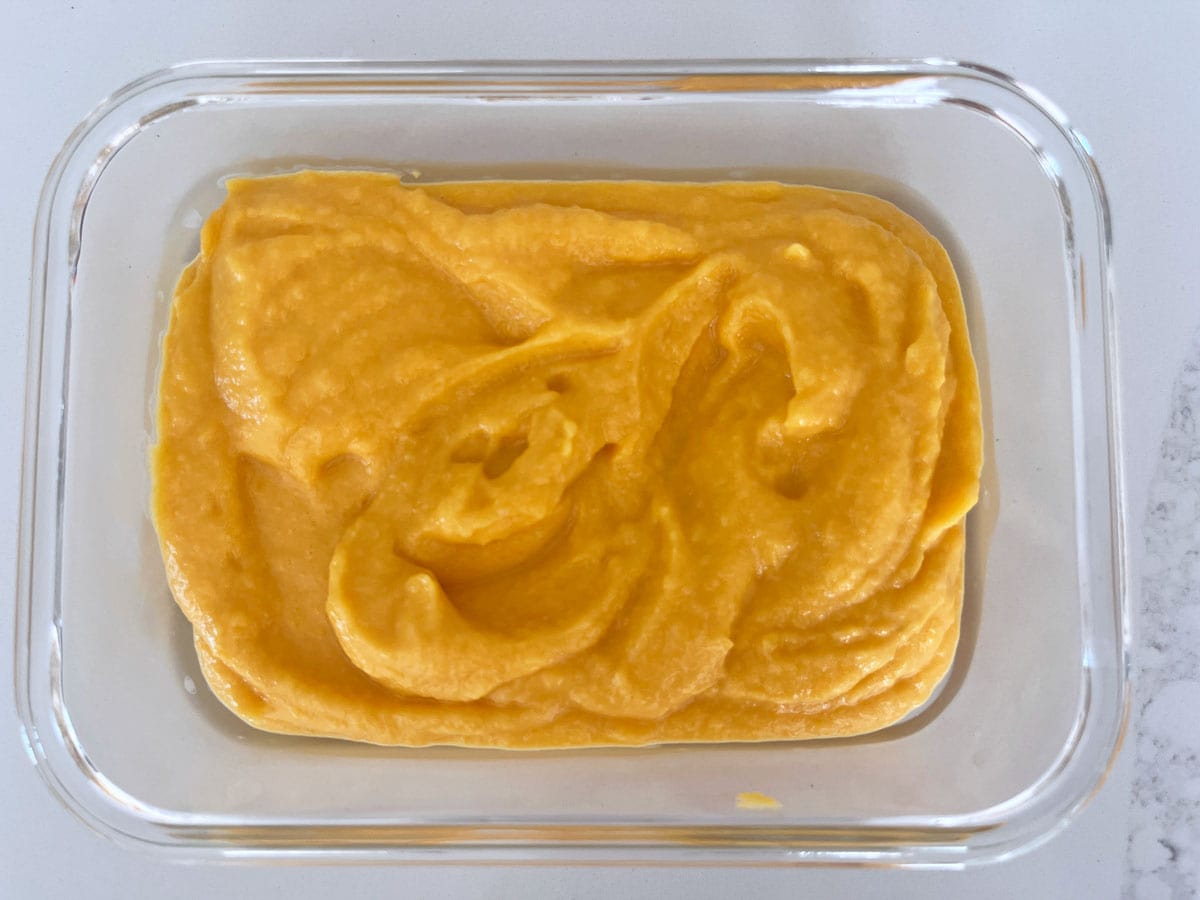 Leftover butternut squash mash are stored in a glass food storage container.