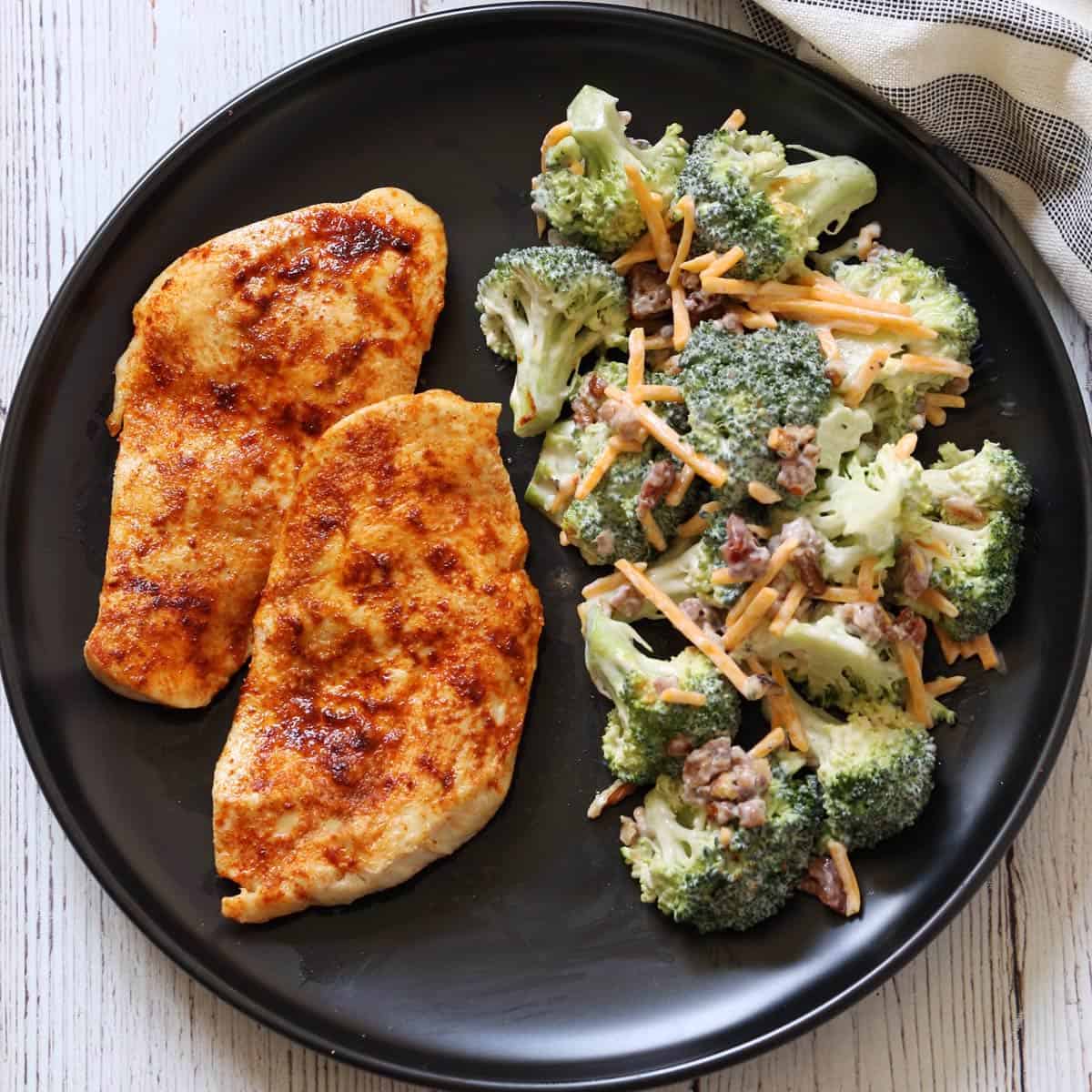 Broccoli salad is served with broiled chicken.