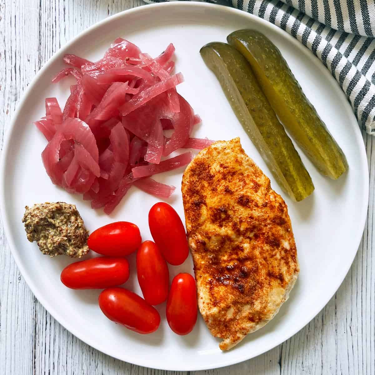Broiled chicken leftovers are served with pickled red onions, Dijon mustard, tomatoes, and dill pickles.