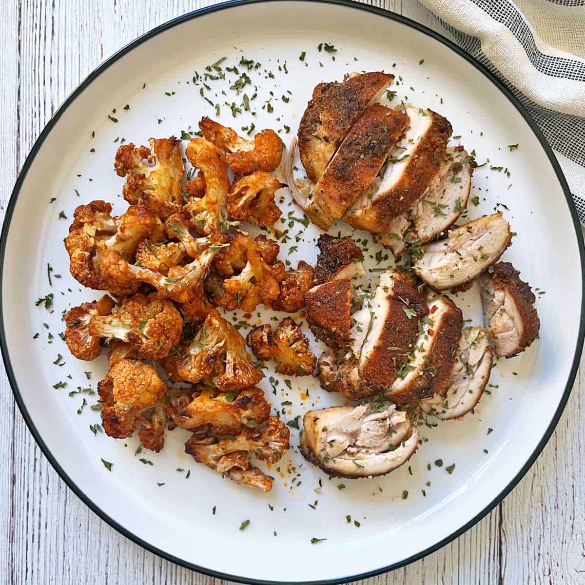 reheated leftovers of Cajun chicken and buffalo cauliflower on a plate.