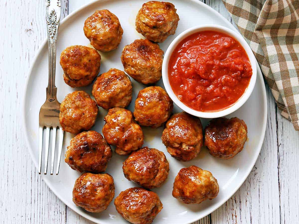 Chicken meatballs are served with a dipping sauce.