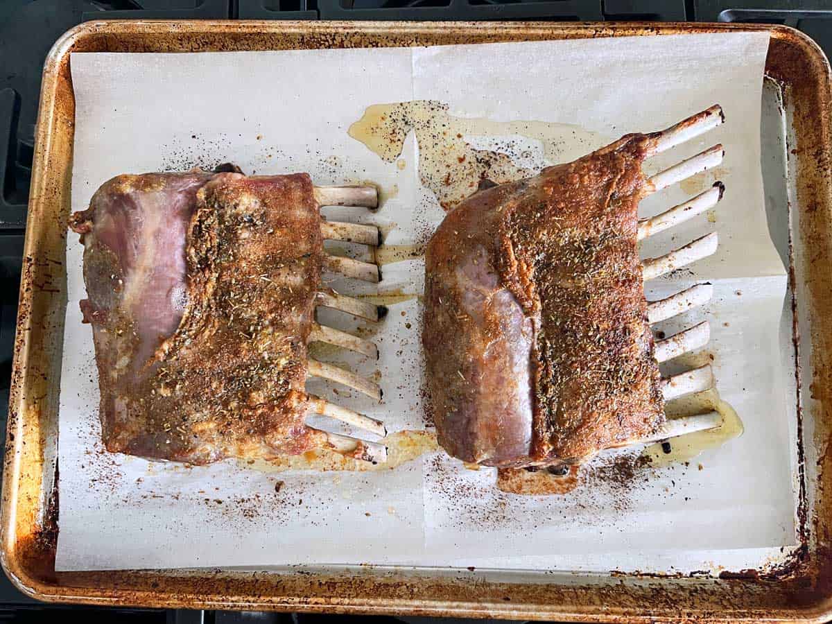 Two racks of lamb on a baking sheet.