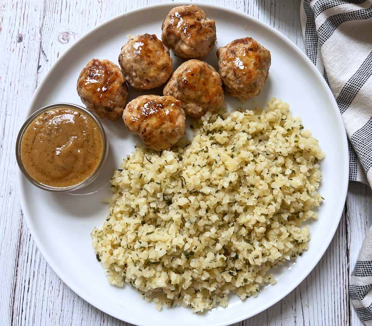 Chicken meatballs and cauliflower rice are served with gravy.