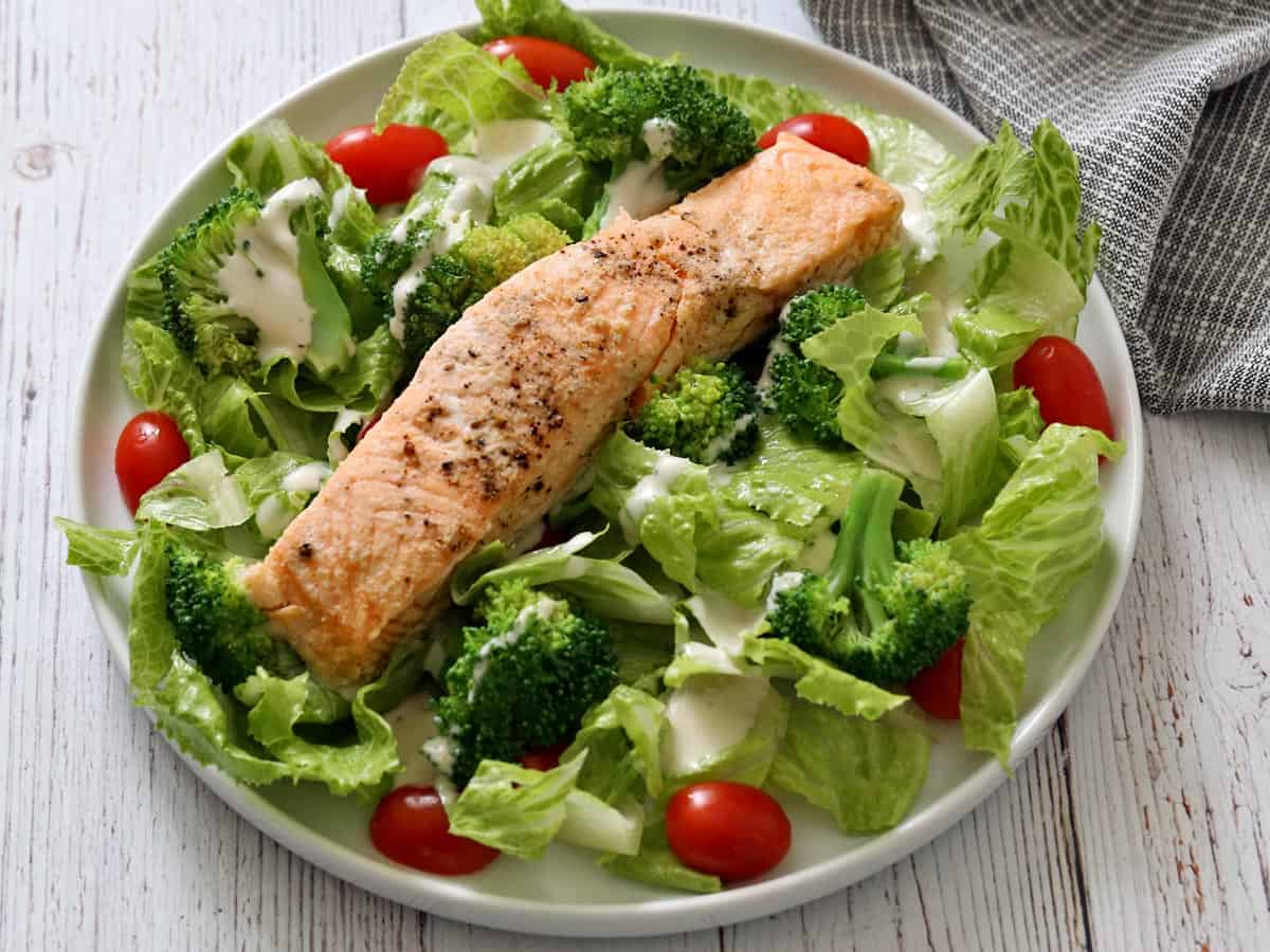 Poached salmon is served on top of a salad.