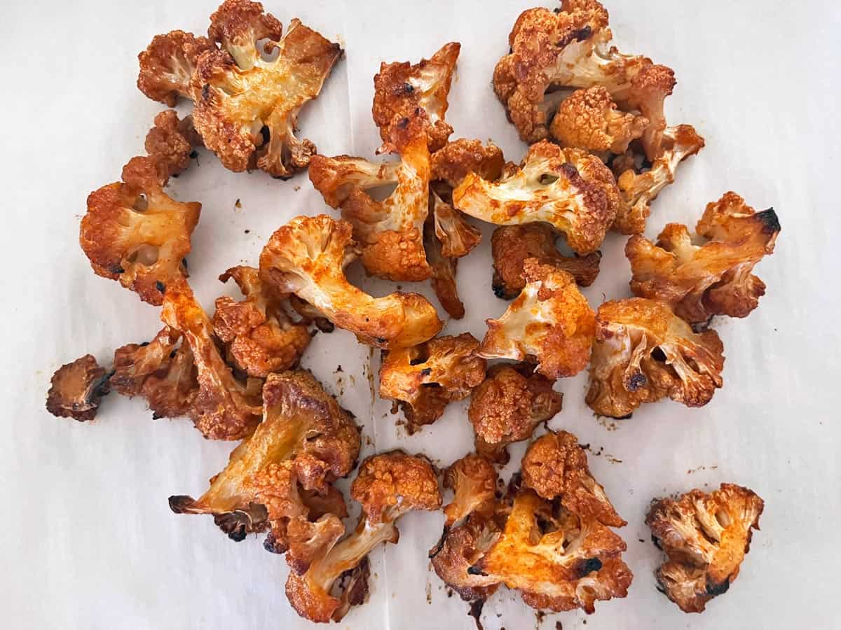 Reheated buffalo cauliflower on a parchment-lined pan.