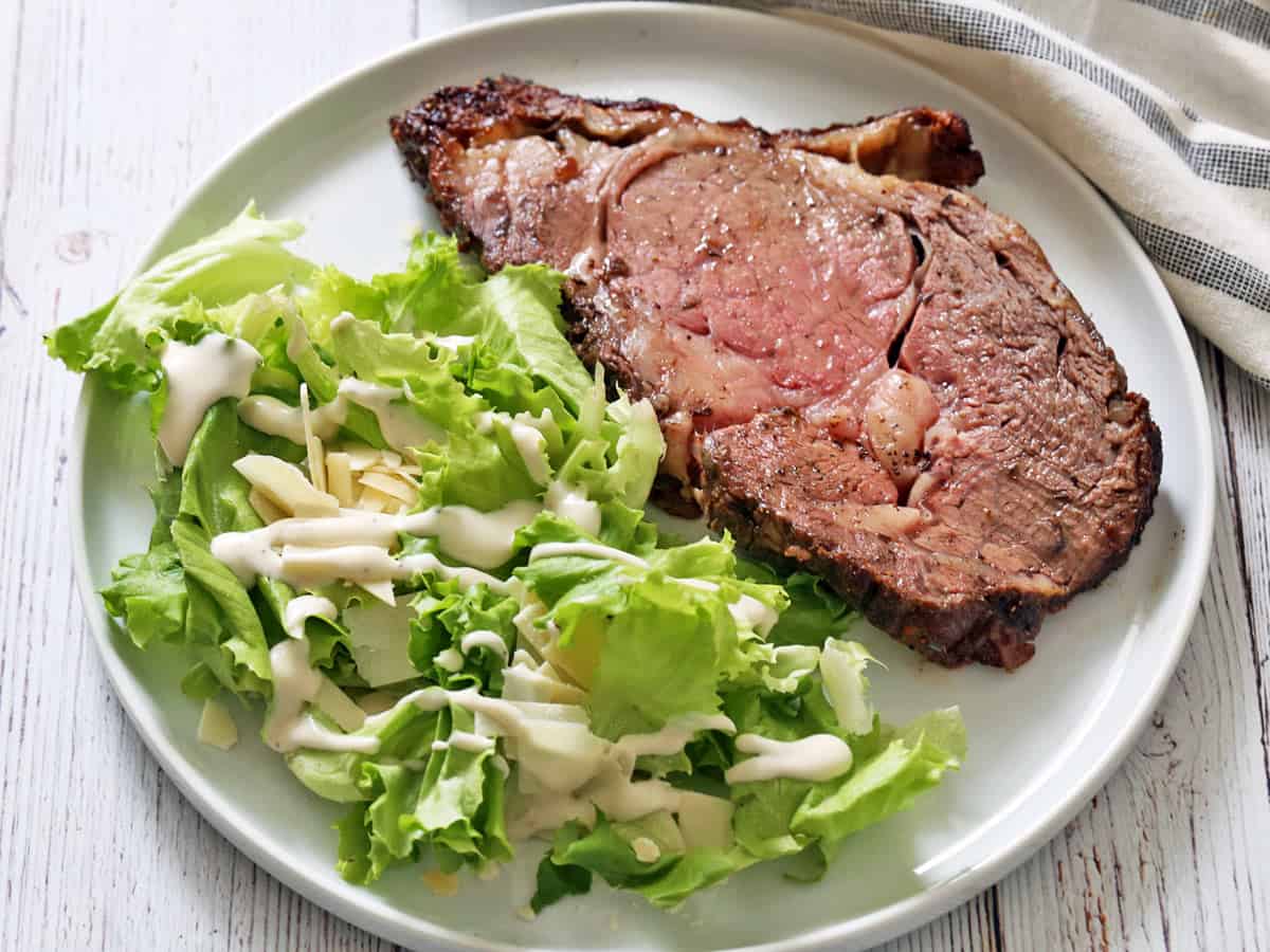 A slice of ribeye roast is served with a salad.