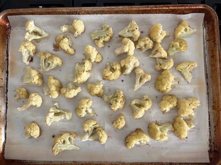 Roasted cauliflower on a parchment-lined baking sheet.