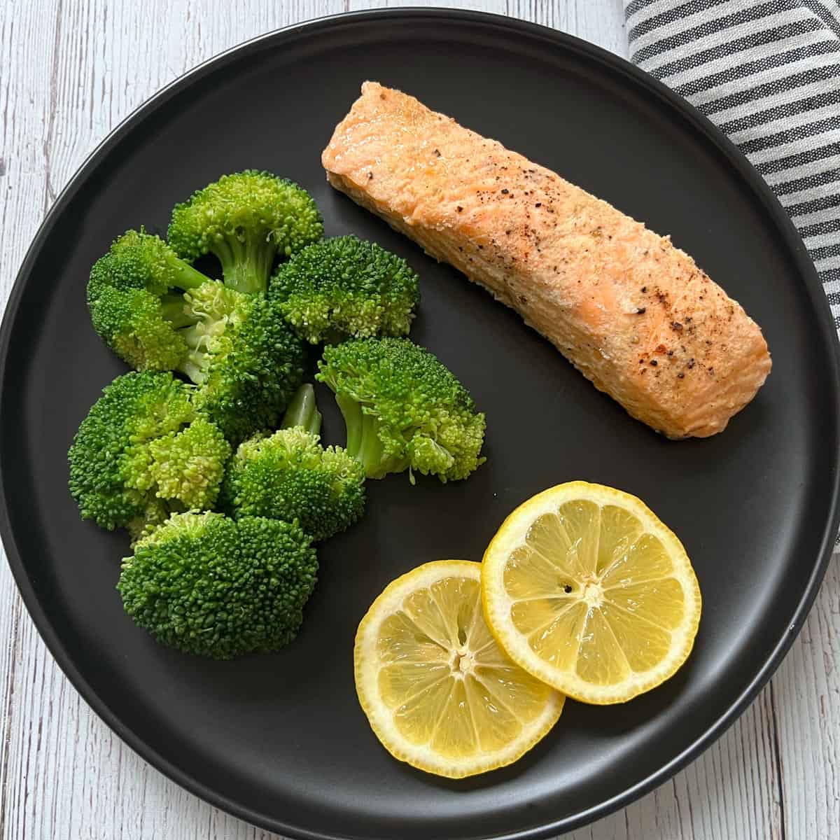 Steamed broccoli is served with poached salmon.
