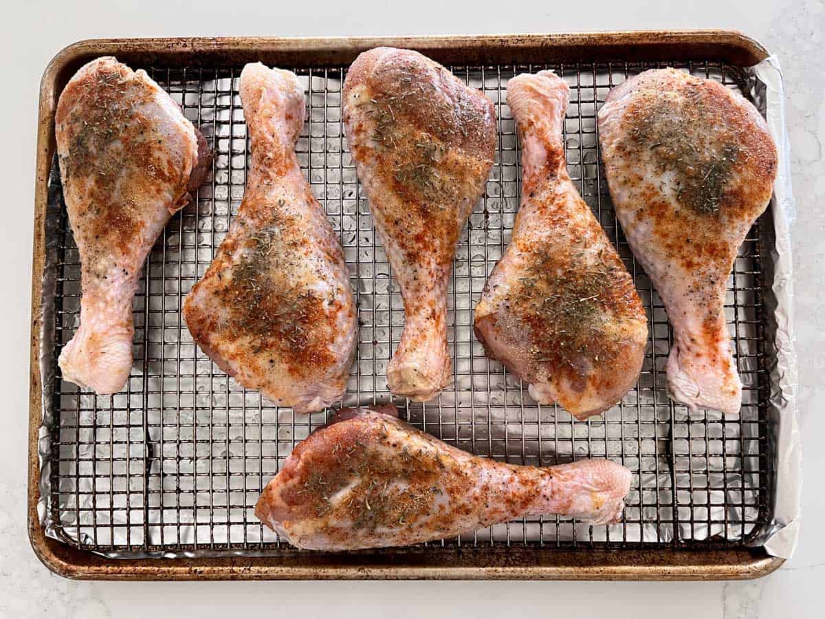 Raw turkey legs on a baking sheet fitted with a roasting rack.
