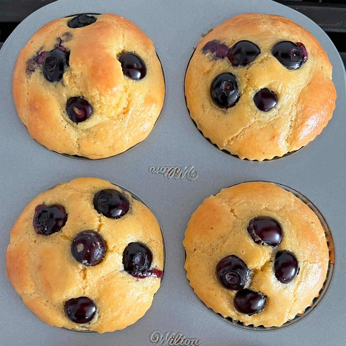 Four almond flour muffins in a muffin pan.