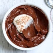 Avocado chocolate mousse is topped with whipped cream.