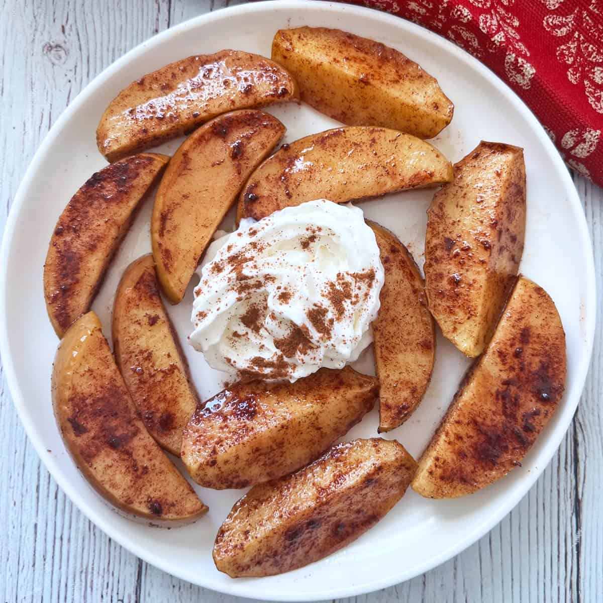 Baked apple slices are served with whipped cream.