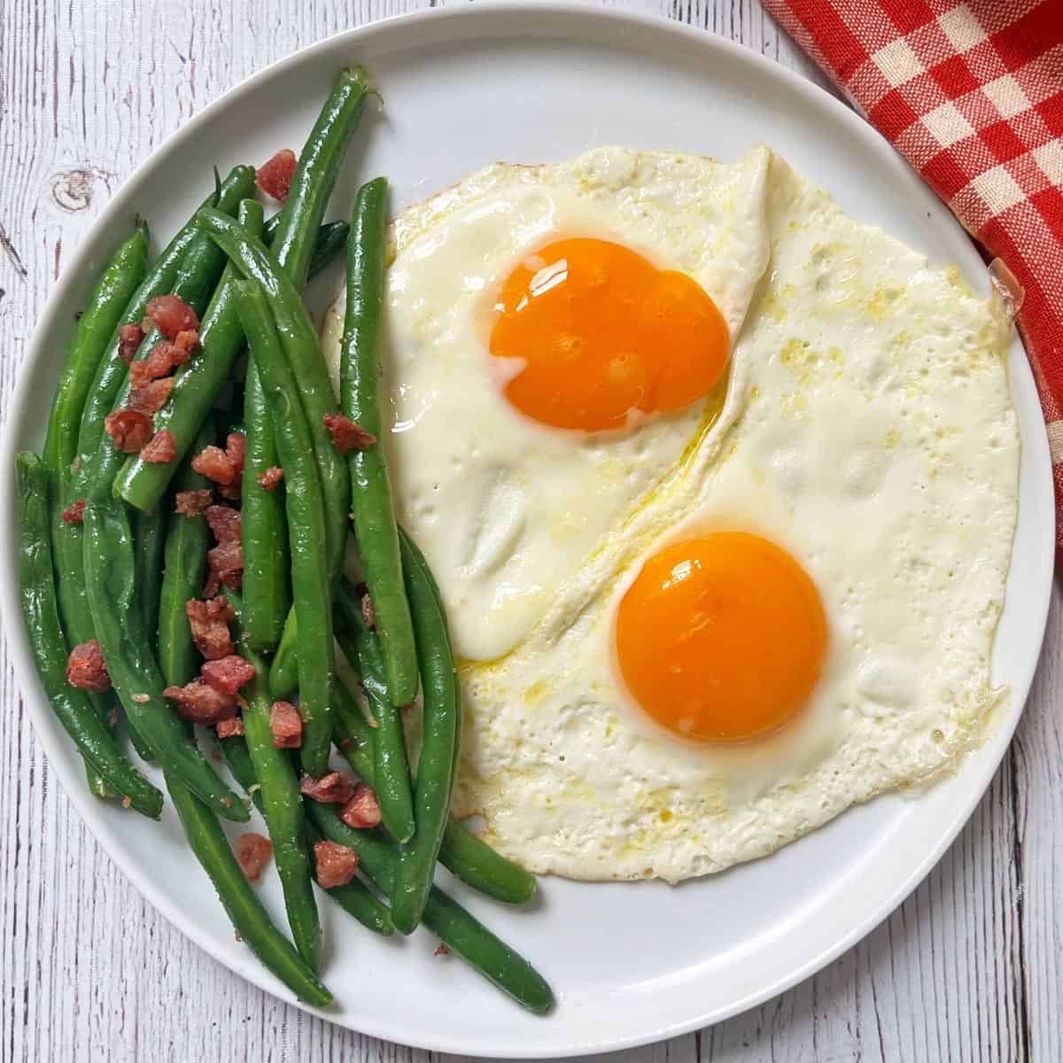 Green beans with bacon are served with eggs.