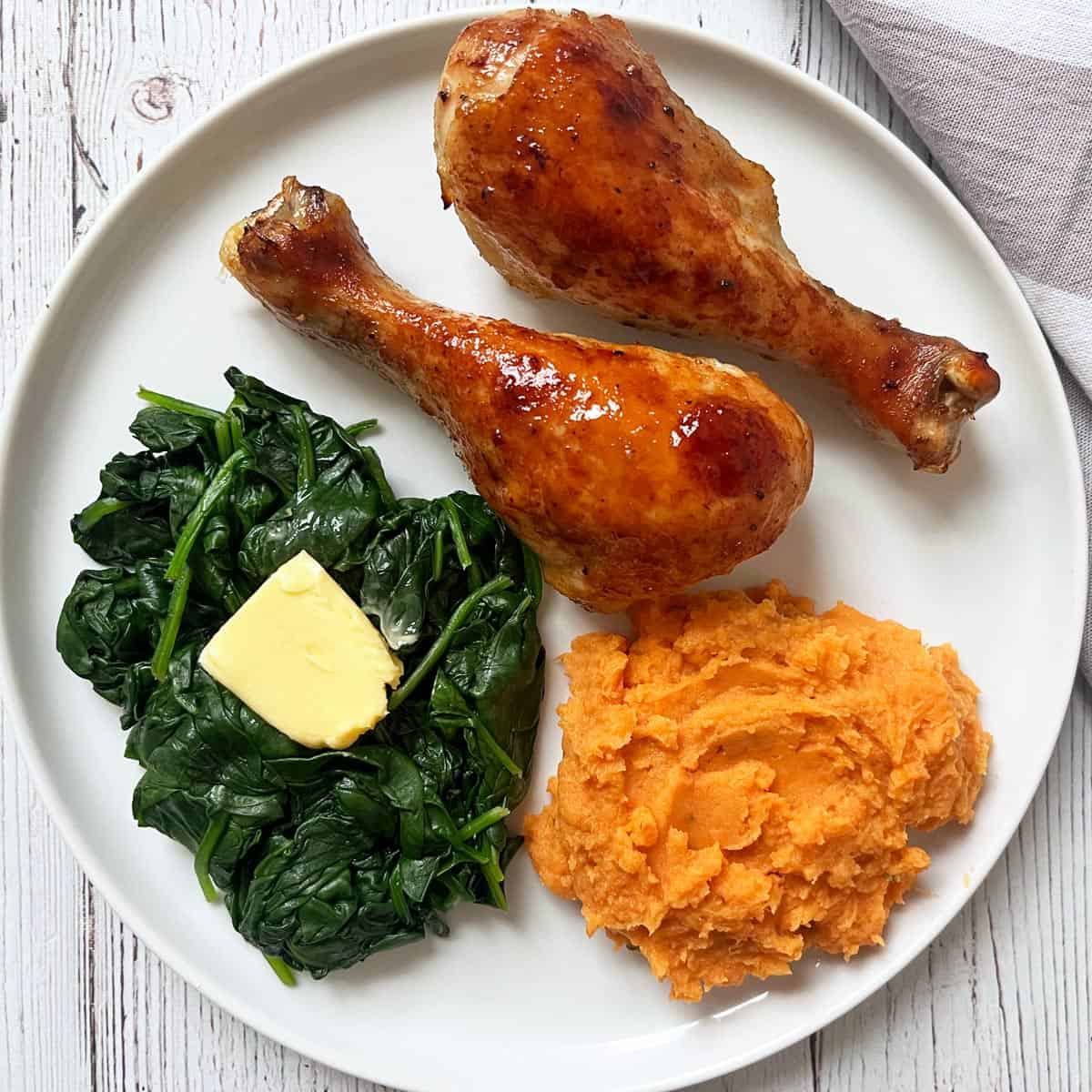 Mashed sweet potatoes are served with chicken and spinach.