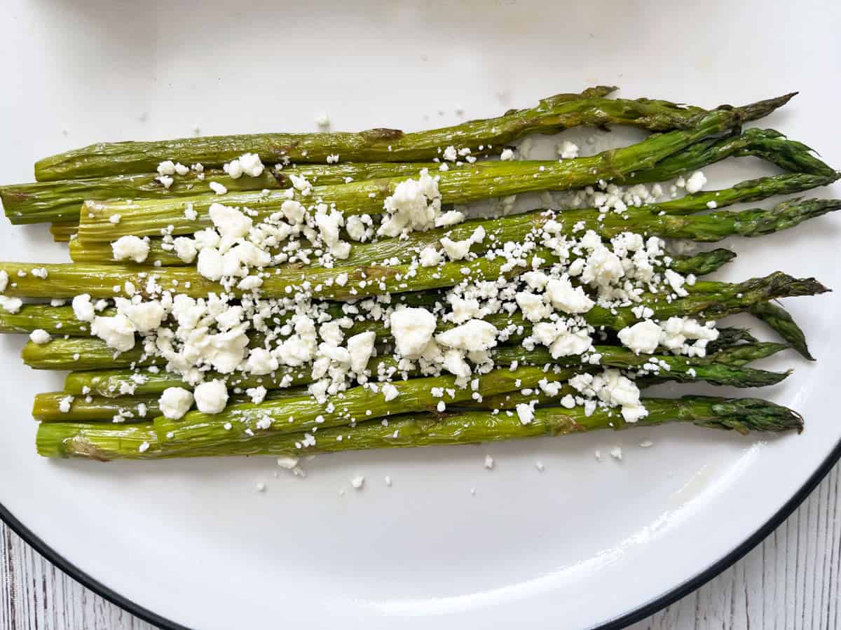 Roasted asparagus is topped with crumbled feta cheese.