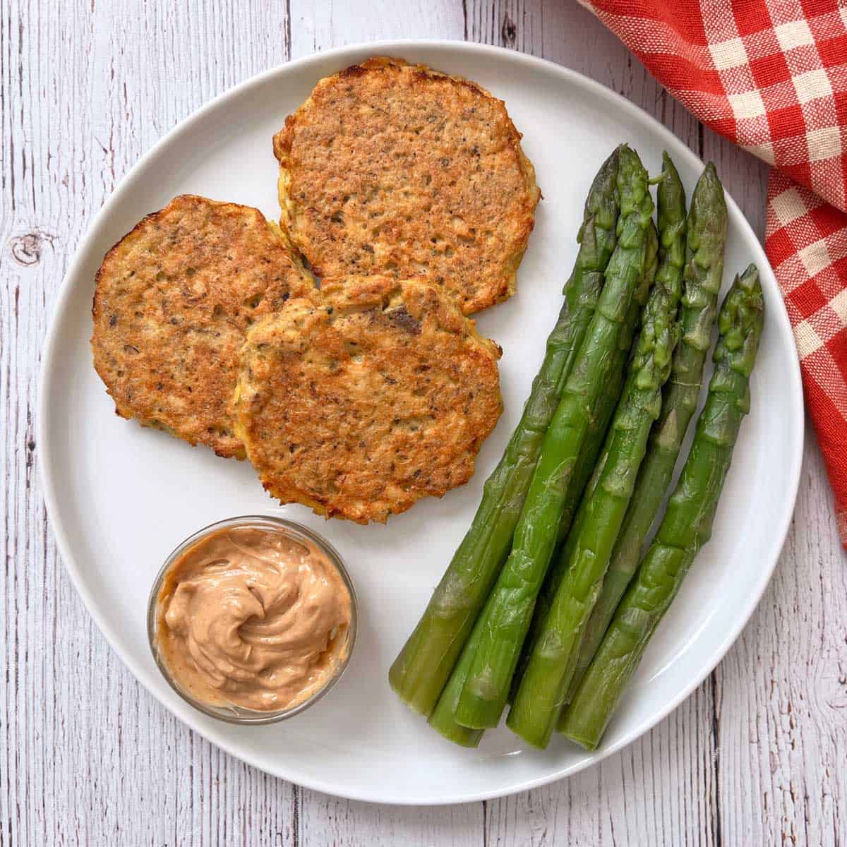 Salmon cakes are served with asparagus.