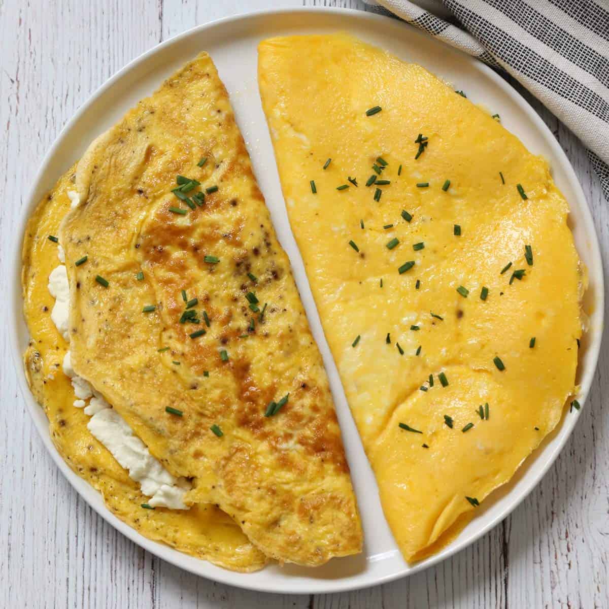 A pale and a browned omelette on a plate.