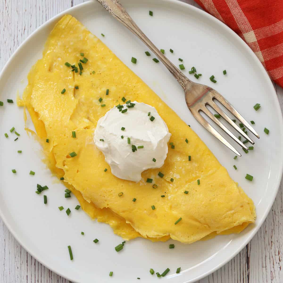 A plain, unfilled omelette is topped with sour cream.