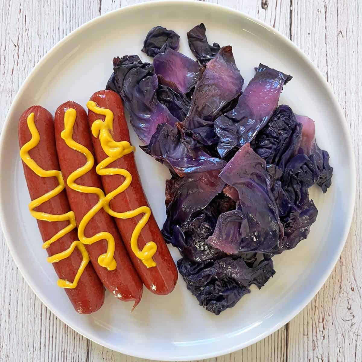 Roasted red cabbage is served with hot dogs.