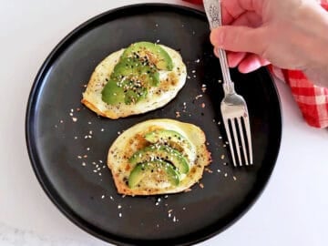 The eggs are served, topped with avocado.