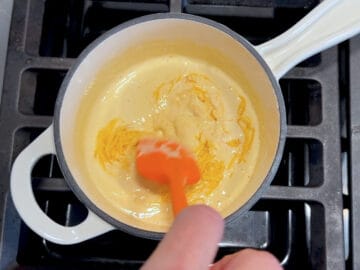 Adding cheese to the heavy cream.