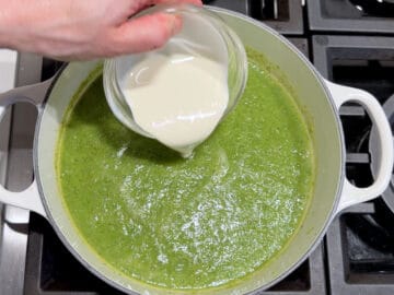 Adding heavy cream to the soup.