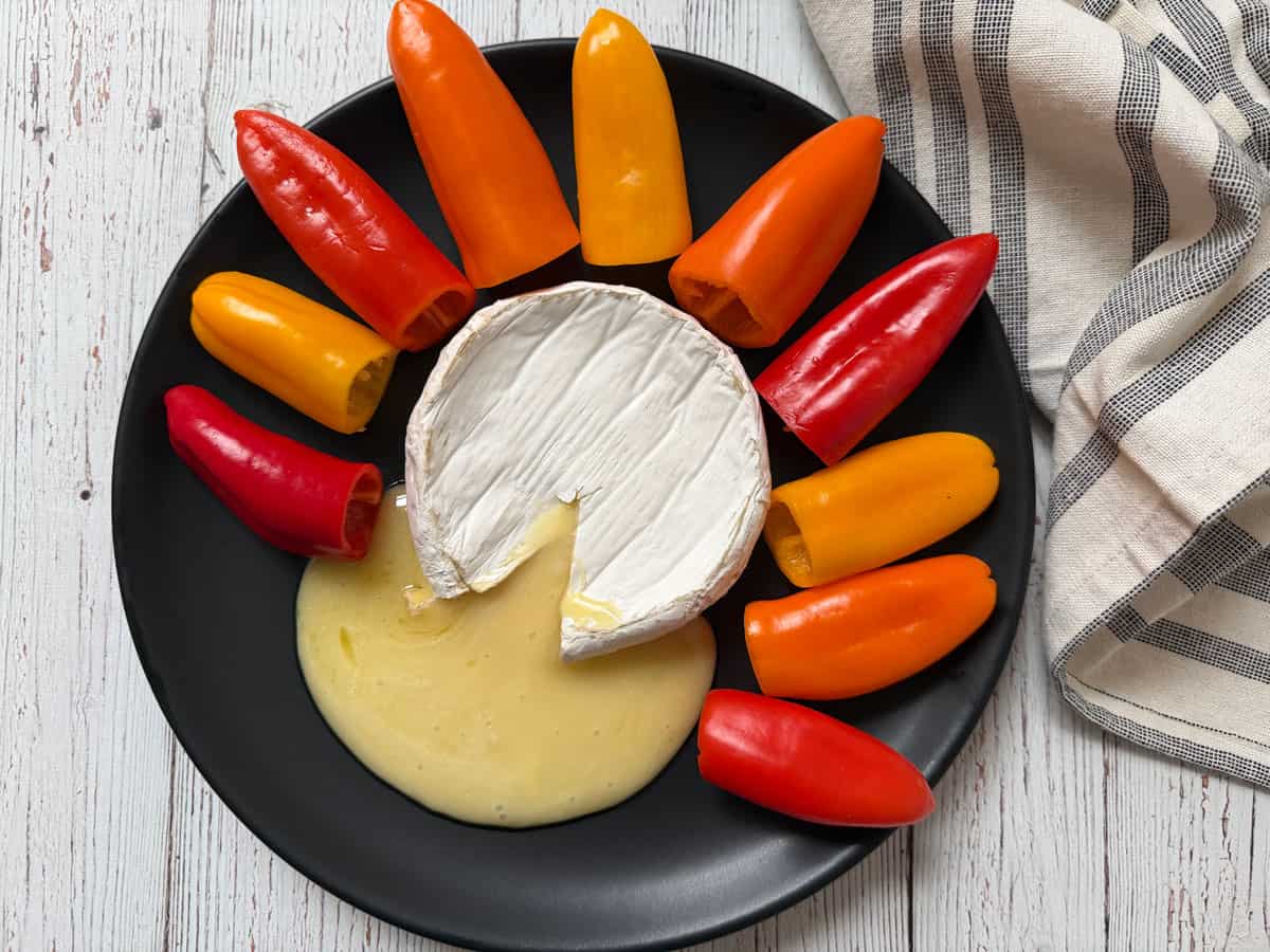 Baked brie is served with mini peppers.