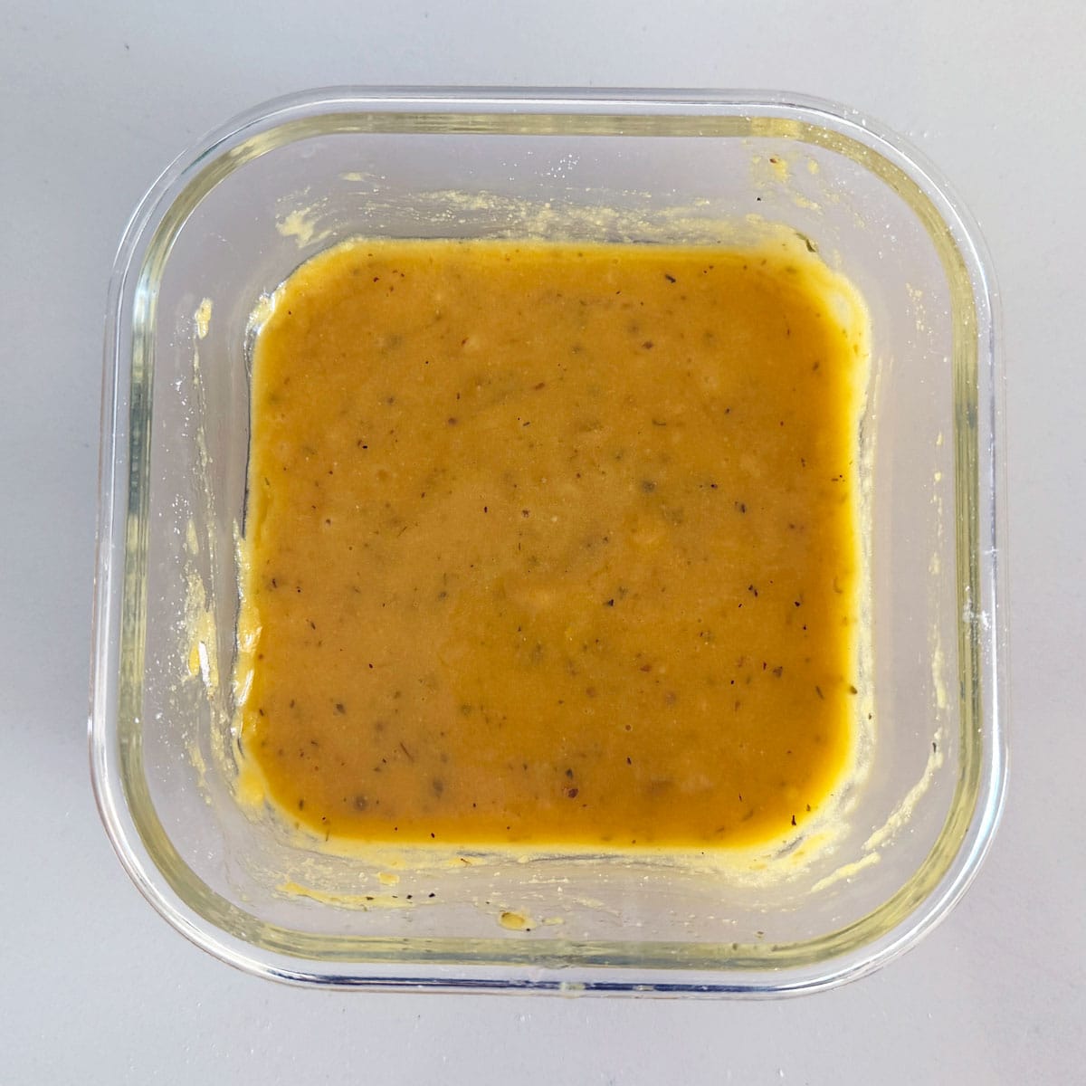 Herb bread batter in a square pan.