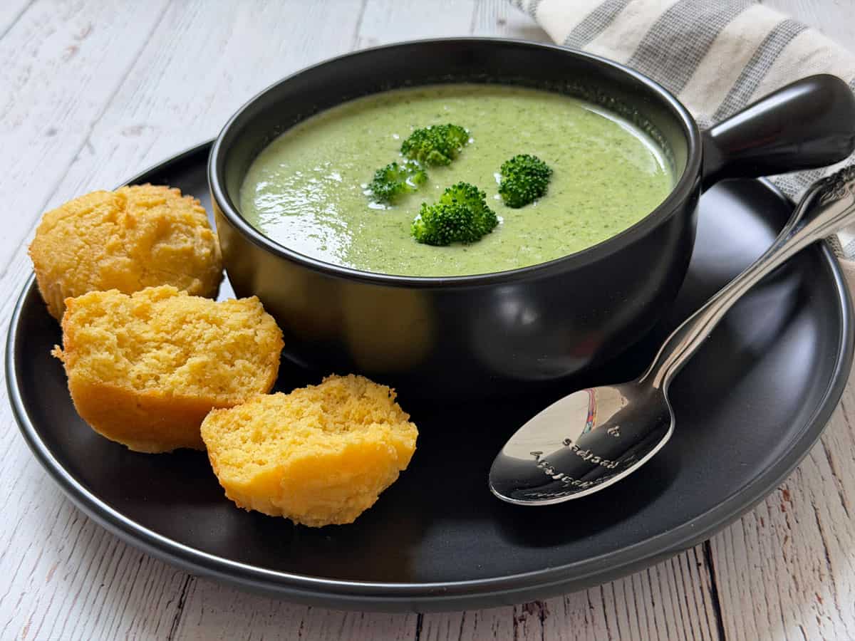 Broccoli soup is served with cornbread muffins.